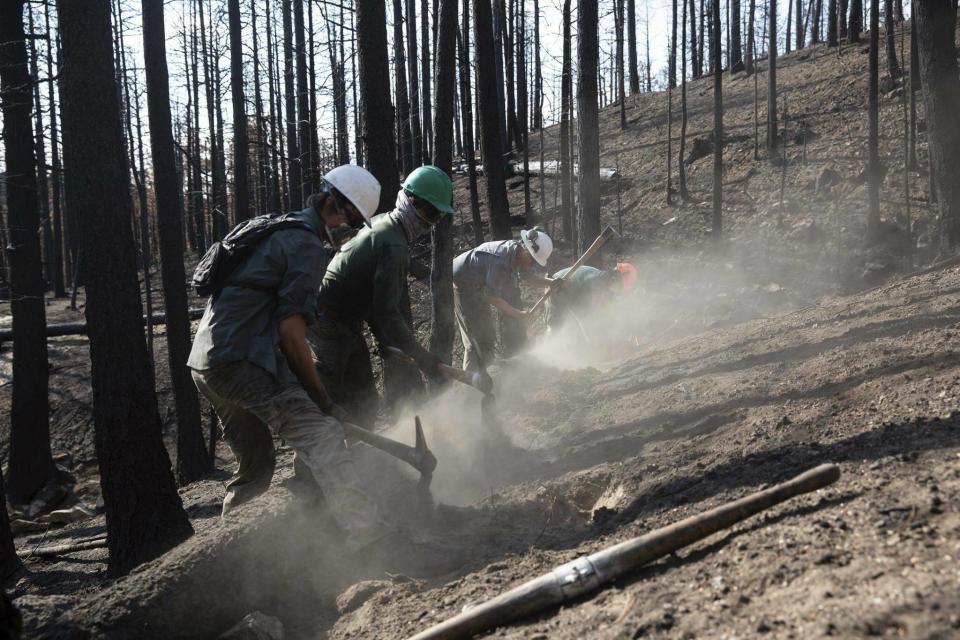 This undated photo provided by the Philmont Scout Ranch shows members of the Philmont Recovery Corps building a series of contours on a charred hillside to limit erosion. The historic ranch near Cimarron, New Mexico, is rebuilding following a devastating wildfire that burned nearly 44 square miles in 2018. Backcountry trails were wiped out along with trail camps. (Shane Mrozek/Philmont Scout Ranch via AP)