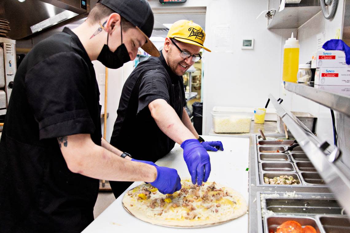 Chef Sam Paskoff, right, and sous chef Josh Springer, left, make a Curry Cubano on Wednesday, March 9, 2022, at Trophy Brewing & Pizza. Trophy boasts one of the Triangle’s most creative pizza menus and was a pioneer in Detroit-style pies that are now all the rage.