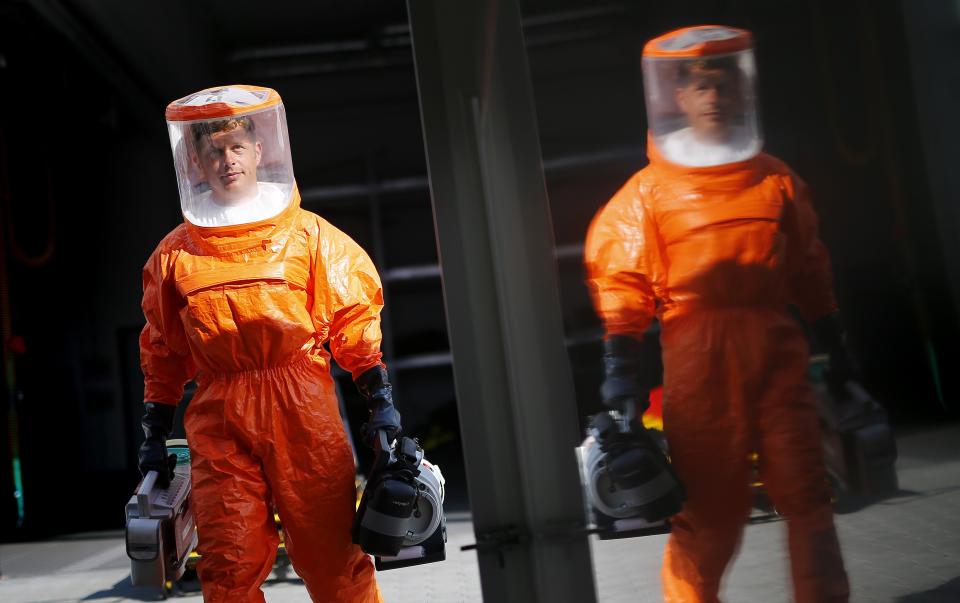 A fire brigade paramedic wearing a sealed protective suit is reflected in a special fire brigade ambulance, as he carries medical equipment into the vehicle during a drill for the crew, in Frankfurt August 21, 2014. The special ambulance is equipped to treat patients suffering from ebola and other highly infectious diseases. Ebola is one of the deadliest diseases known to humanity. It has no proven cure and there is no vaccine to prevent infection. The rigorous use of quarantine is needed to prevent its spread, as well as high standards of hygiene for anyone who might come into contact with the disease. REUTERS/Kai Pfaffenbach (GERMANY - Tags: HEALTH TPX IMAGES OF THE DAY)