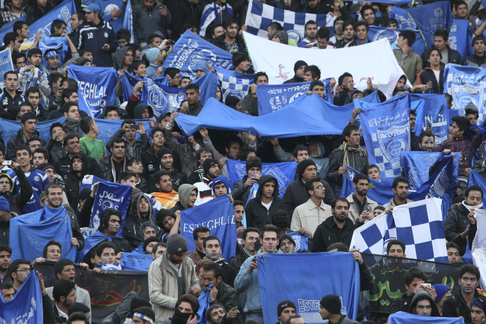 FILE - In this Dec. 9, 2011 file photo, supporters of Iranian soccer team Esteghlal, hold flags of their favorite team, at the Azadi (Freedom) stadium, in Tehran, Iran. Sahar Khodayari, an Iranian female soccer fan died after setting herself on fire outside a court after learning she may have to serve a six-month sentence for trying to enter a soccer stadium where women are banned, a semi-official news agency reported Tuesday, Sept. 10, 2019. The 30-year-old was known as the "Blue Girl" on social media for the colors of her favorite Iranian soccer team, Esteghlal. (AP Photo/Vahid Salemi, File)