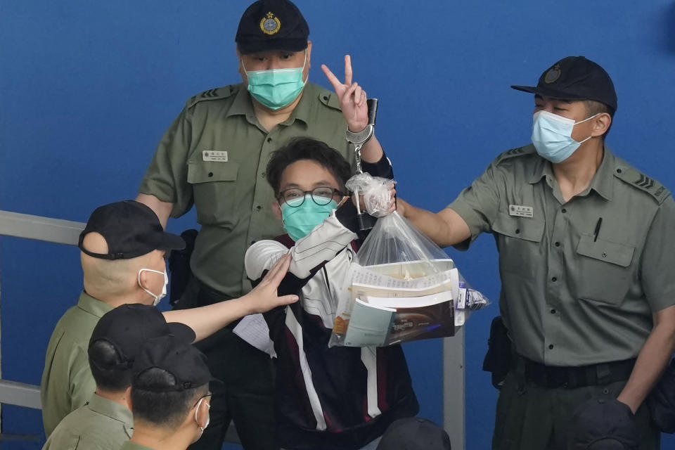 Pro-democracy activist Figo Chan shows a victory sign as he is escorted by Correctional Services officers to a prison van for a court in Hong Kong, Friday, May 28, 2021. Jimmy Lai and nine others, including Chan, accused of "incitement to knowingly take part in an unauthorized assembly" on Oct. 1, 2019, were sentencing in court. Lai is already serving a 14-month sentence for his role in two other unauthorized assemblies during a period when Hong Kong residents were involved in mass anti-government protests. (AP Photo/Kin Cheung)