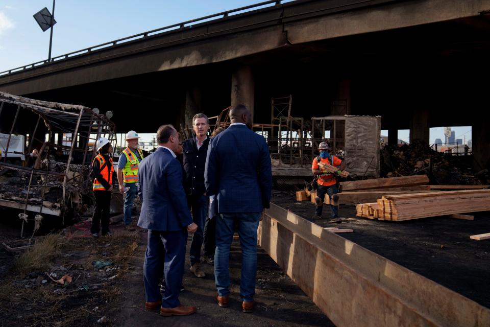 California Gov. Gavin Newsom, center, tours the site of a fire that erupted Saturday under Interstate 10, in Los Angeles, Monday, Nov. 13, 2023.