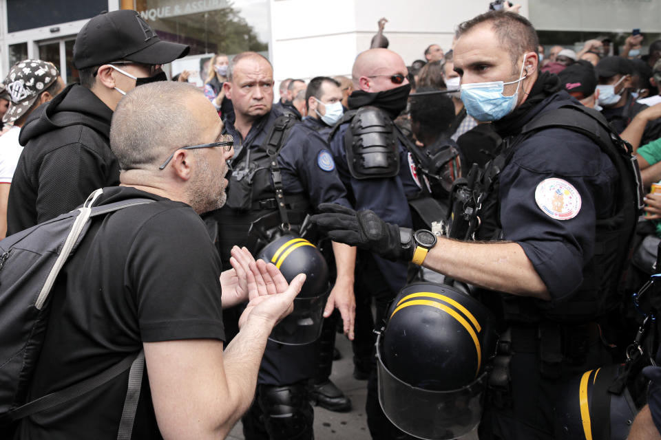A riot police officer gestures while speaking to a demonstrator during a protest in memory of Lamine Dieng, a 25-year-old Franco-Senegalese who died in a police van after being arrested in 2007, in Paris, Saturday, June 20, 2020. Multiple protests are taking place in France on Saturday against police brutality and racial injustice, amid weeks of global anger unleashed by George Floyd's death in the US. (AP Photo/Christophe Ena)