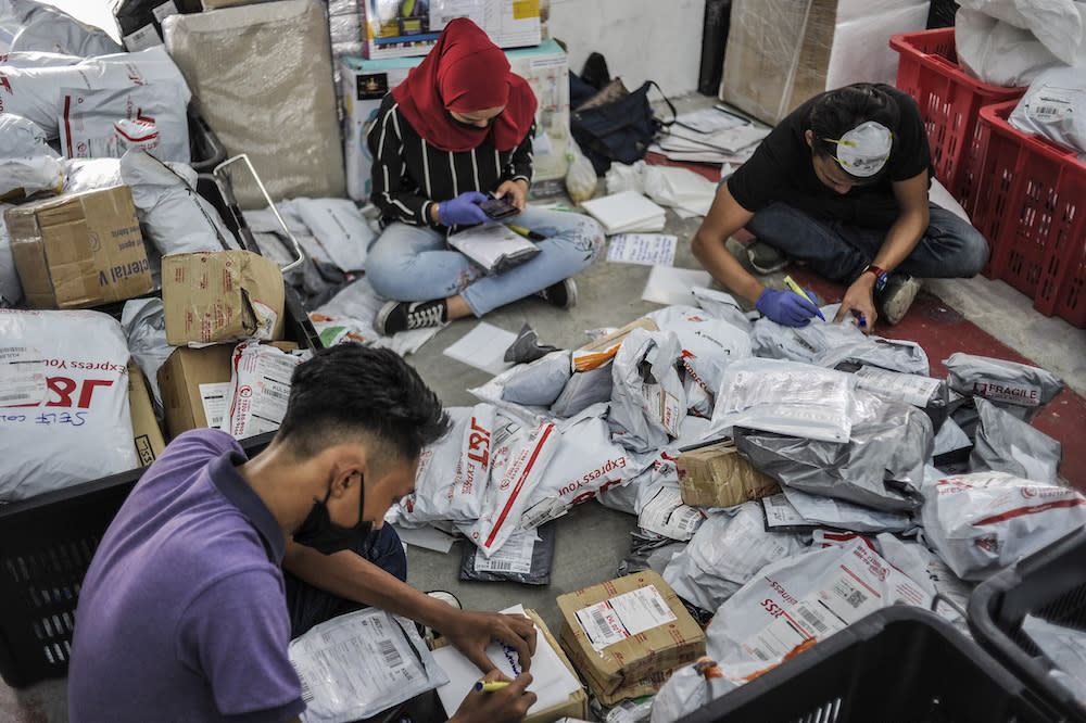 Staff of courier service company J&amp;T Express check parcels that are ready for delivery at their warehouse in Seri Rampai April 7, 2020.  MCMC said as of October 2020, there are 109 courier service licence holders of various categories which are operating in Malaysia.— Picture by Shafwan Zaidon