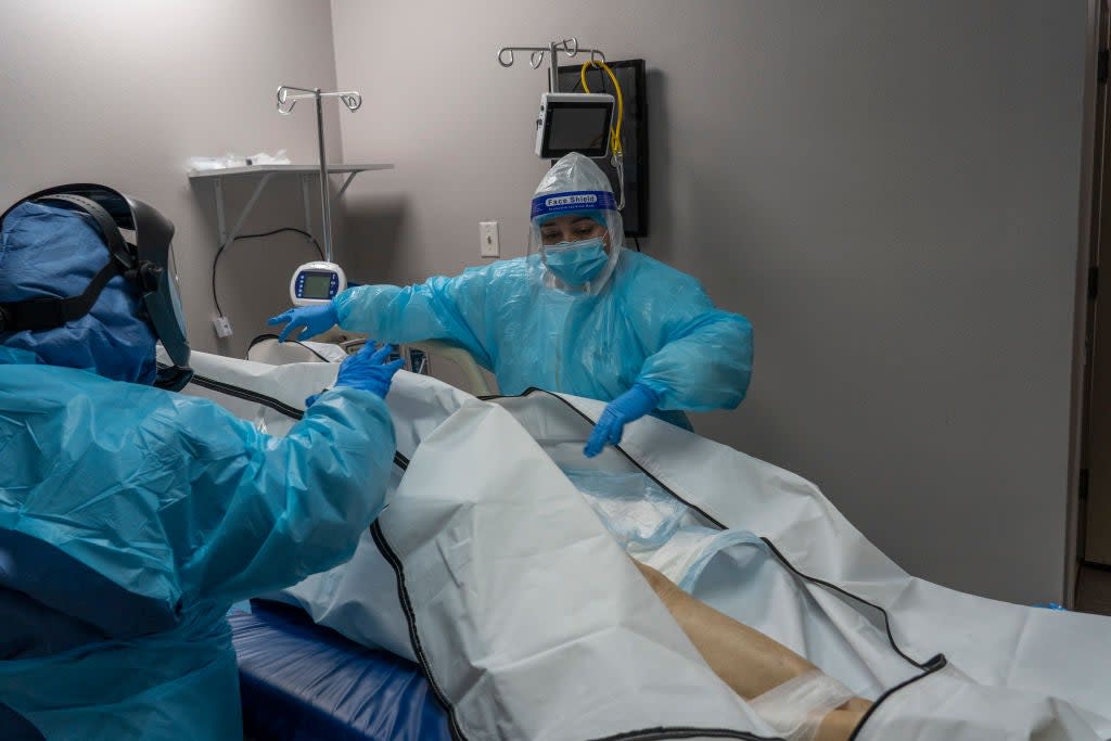 Medical staff at a hospital in Houston, Texas, close the body bag of a deceased Covid-19 patient (Go Nakamura/Getty Images)