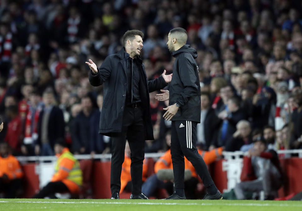 Atletico coach Diego Simeone, left, talks to an assistant referee during the Europa League semifinal first leg soccer match between Arsenal FC and Atletico Madrid at the Arsenal stadium in London, Britain, Thursday, April 26, 2018. (AP Photo/Tim Ireland)