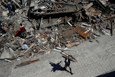 A man carries wooden planks salvaged from the rubble of a destroyed houses after Hurricane Matthew passes in Jeremie, Haiti, October 8, 2016. REUTERS/Carlos Garcia Rawlins