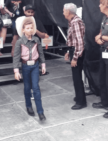 Mason Ramsey spins around and does finger guns while wearing a cowboy hat