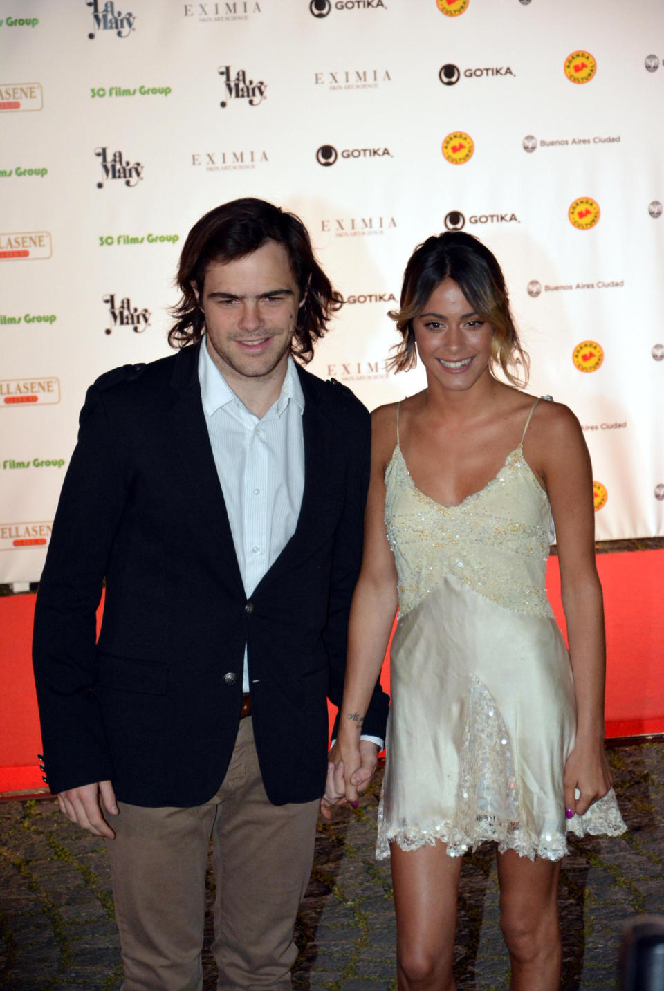 2014. Acá veíamos a una Tini de 17 años, de la mano con su entonces novio, el actor argentino Peter Lanzani. En aquel entonces, la actriz también optaba por el slip dress, aunque con encajes, brillos ¡y muy corto! - Foto: Virtual Press