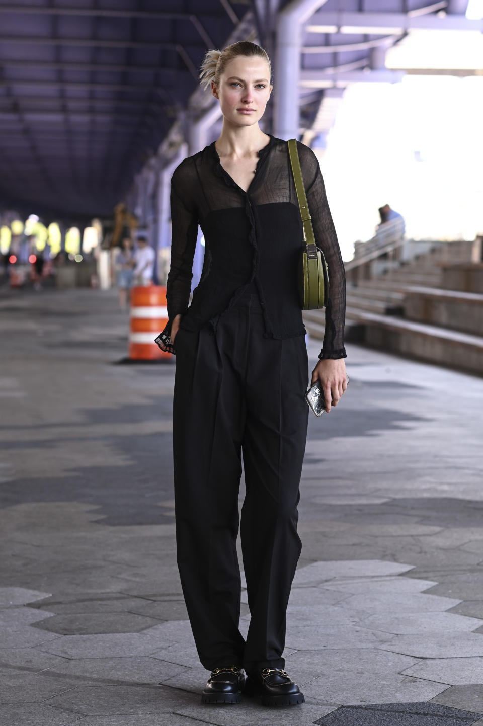 woman in black pants, tank top, and sheer shirt