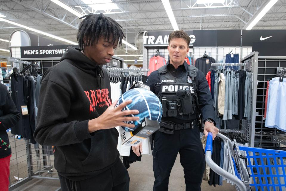 Pensacola Police Department officer Dave Partrick, right, looks on as Danylen Moorer, 17, picks out a basketball during the Shop with a Cop shopping spree at the Academy Sports + Outdoors in Pensacola on Thursday, Dec. 21, 2023.