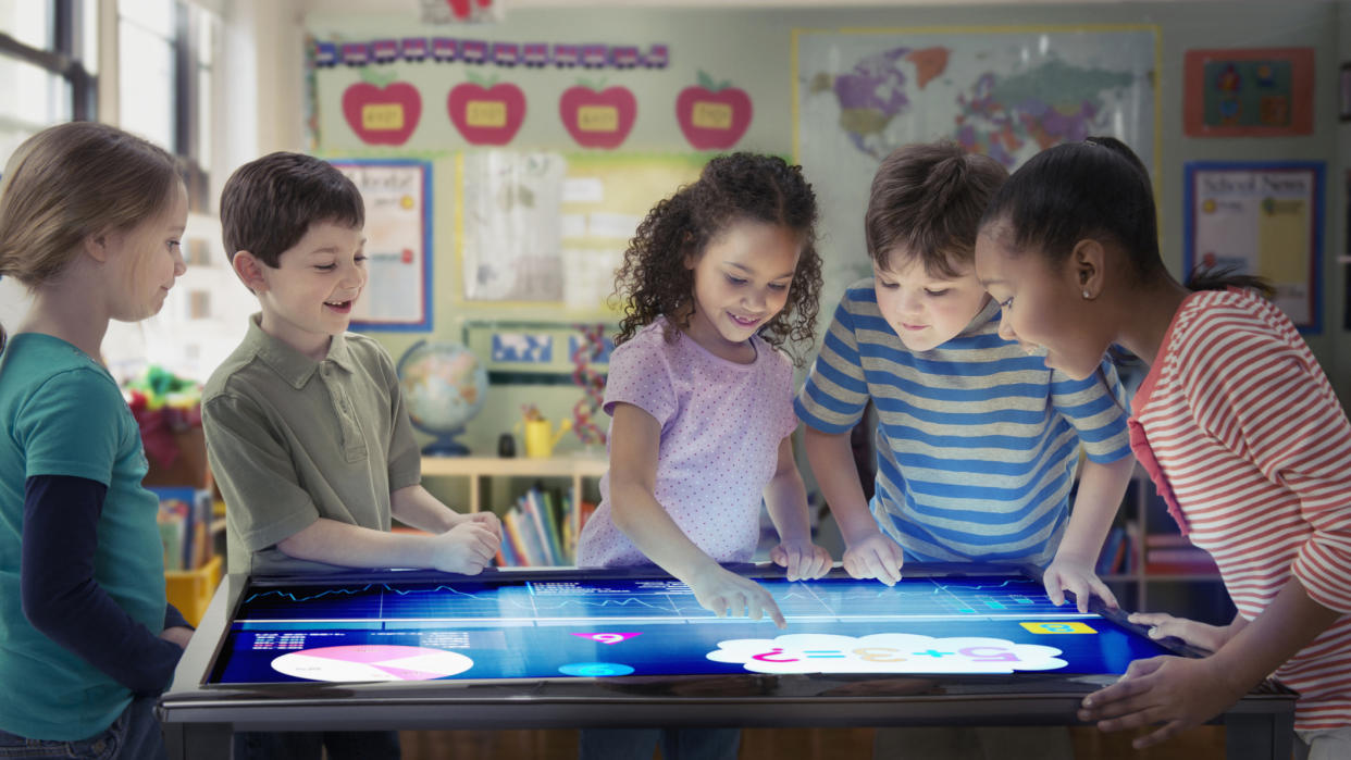  Smiling kids playing with technology in a classroom. 