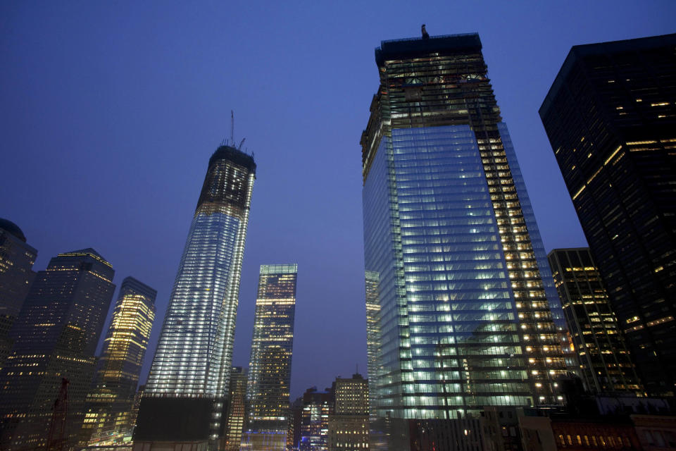 One World Trade Center, left, now up to the 100th floor, and Four World Trade Center, right, overlook the ongoing construction of the site, Sunday, April 1, 2012 in New York. The unfinished One World Trade Center is one of the city's tallest structures. If construction continues at its current pace, it will pass the Empire State Building this spring. Four WTC will top out at 72 floors. (AP Photo/Mark Lennihan)