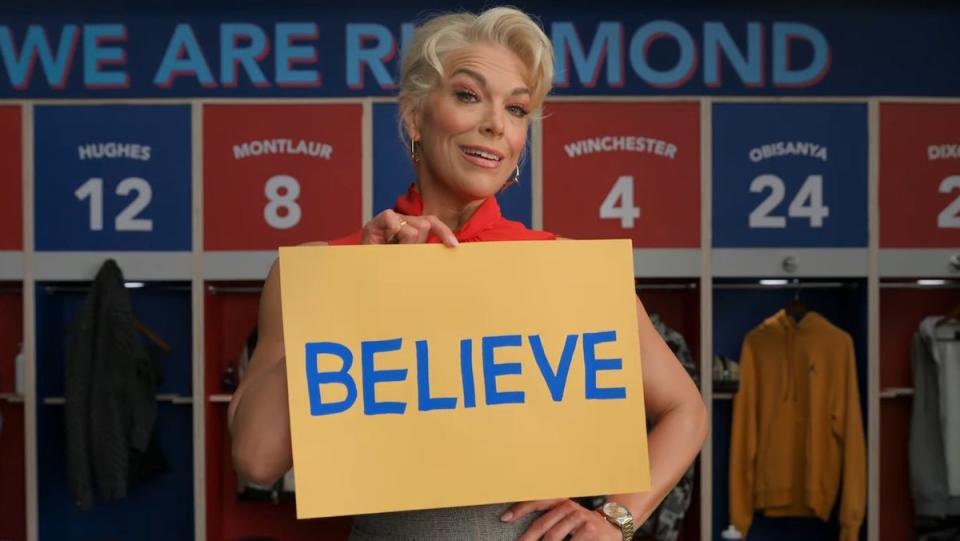 Ted Lasso season three 3 teaser reveals Hannah Waddingham's rebecca holds a yellow and blue Believe sign in front of AFC Richmond's locker room.