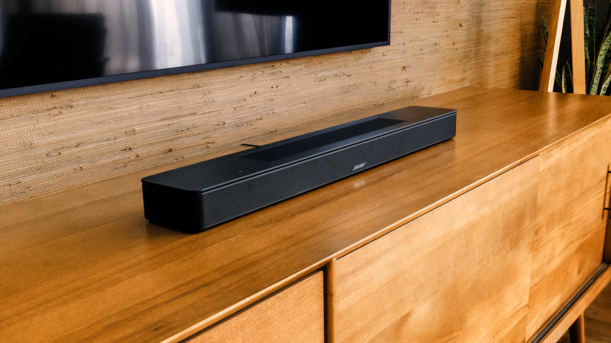  Bose Soundbar 600 on a wooden table beneath a TV. 