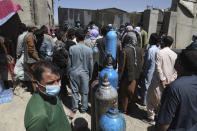 Men wait outside a privately owned oxygen factory to get their oxygen cylinders refilled, in Kabul, Afghanistan, Saturday, June 19, 2021. Health officials say Afghanistan is fast running out of oxygen as a deadly third surge of COVID worsen. (AP Photo/Rahmat Gul)