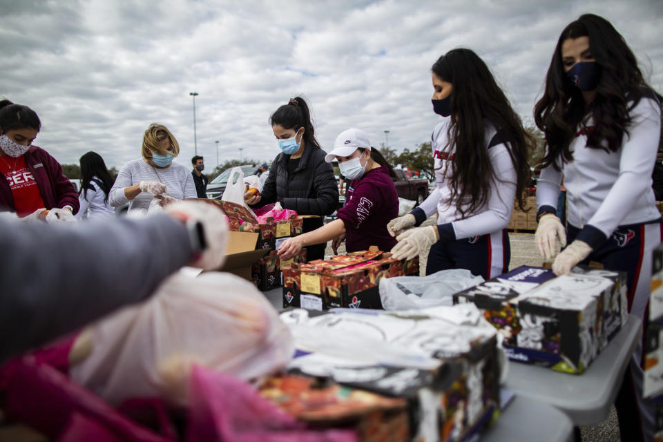 Texans Cheerleaders and other volunteers pack food to distribute to hundreds of people picking up supplies from their cars after frigid temperatures left the Houston area depleted of resources, Sunday, Feb. 21, 2021, in Houston. (Marie D. De Jesús/Houston Chronicle via AP)