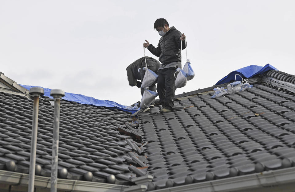 Employees try to cover the destroyed roof with blue sheets in preparation for rain and snow at a nursing home in Shika town, Ishikawa prefecture, Japan Sunday, Jan. 7, 2024. A major earthquake slammed western Japan on Jan. 1, killing scores of people, toppling buildings and setting off landslides. (Kyodo News via AP)