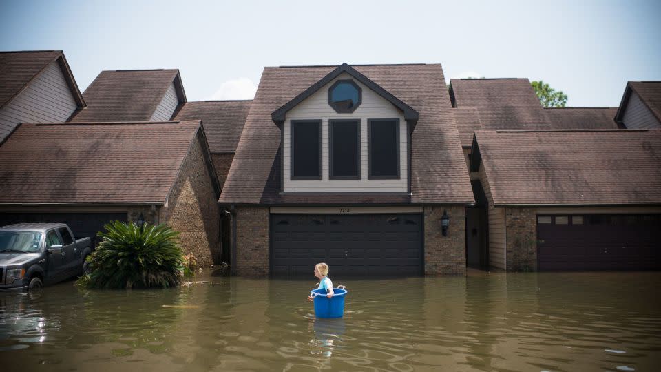 Jenna Fountain carries a bucket to recover items in Port Arthur, Texas, after Hurricane Harvey in 2017. - Emily Kask/AFP/Getty Images