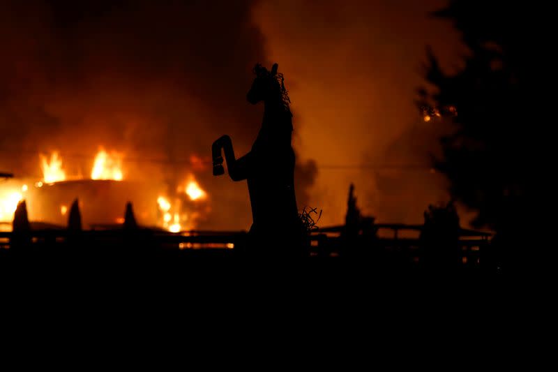 FILE PHOTO: A horse statue is silhouetted by a burning structure during the wind-driven Kincade Fire in Windsor, California