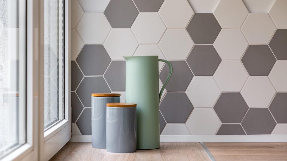 Close-up of ceramic containers, jug and hexagon tiles in kitchen.