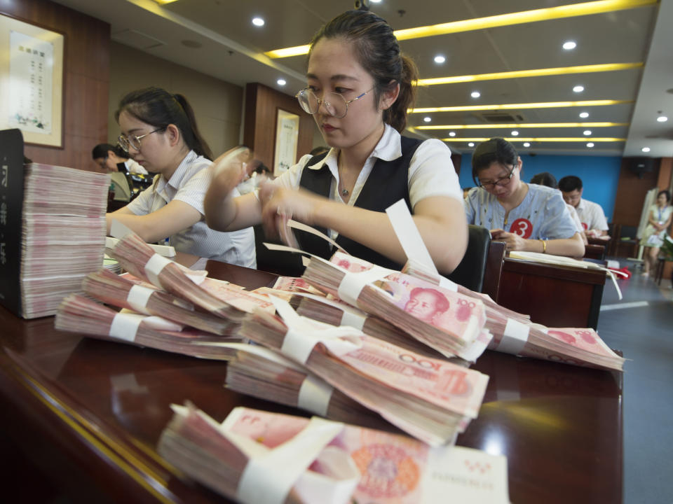 A bank clerk counts RMB (renminbi) yuan banknotes. (Source: Imaginechina via AP Images)