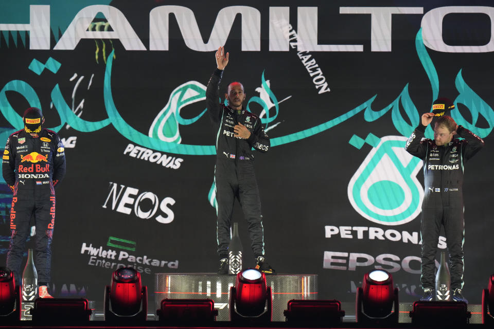 Mercedes driver Lewis Hamilton of Britain waves from the podium after winning the Formula One Saudi Arabian Grand Prix in Jiddah, Sunday, Dec. 5, 2021. Left is second placed Red Bull driver Max Verstappen of the Netherlands and Ron the right is third, Mercedes driver Valtteri Bottas of Finland. (AP Photo/Hassan Ammar)