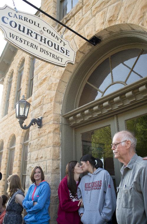 Jennifer Rambo, left, of Jacksonville, Ark., kisses her partner Kristin Seaton, right, of Fort Smith, Ark., as they wait in line at the Carroll County Courthouse to apply for a marriage license, Saturday, May 10, 2014, in Eureka Springs, Ark. Rambo and Seaton drove to Eureka Springs Friday night and slept in their car after a judge overturned Amendment 83, which banned same-sex marriage in the state of Arkansas. (AP Photo/Sarah Bentham)