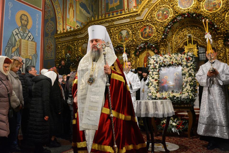An Orthodox priest, in ceremonial robes of white, red, and gold, holds a scepter and leads a service in a gold-decked church in Kyiv, Ukraine.