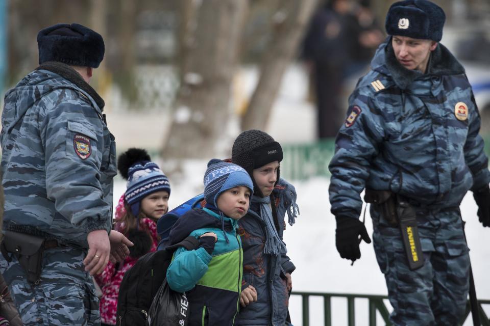 Police officers evacuate children from a Moscow school on Monday, Feb. 3, 2014. An armed teenager burst into his Moscow school on Monday and killed a teacher and policeman before being taken into custody, investigators said. None of the children who were in School No. 263 were hurt, said Karina Sabitova, a police spokeswoman at the scene. The student also wounded a second police officer who had responded to an alarm from the school, she said. (AP Photo/Alexander Zemlianichenko)