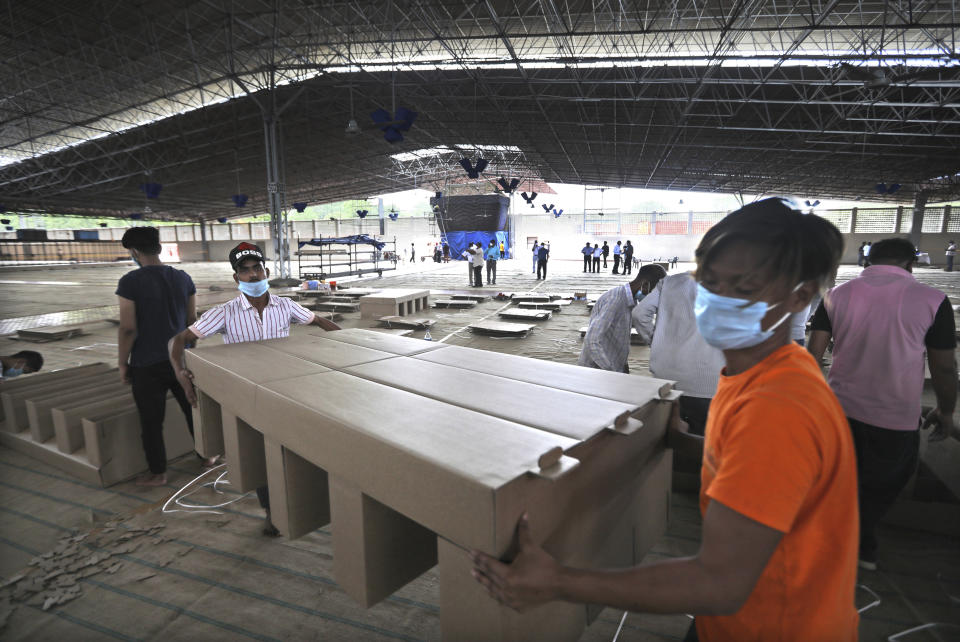 Workers carry cardboard beds after assembling as they prepare a facility that can accommodate more than ten thousand COVID-19 patients at the Radha Soami Satsang Beas complex, one off the biggest in India, in the Chattarpur area of New Delhi, India, Wednesday, June 24, 2020. New Delhi, which is among India's worst hit three states is emerging a cause of concern for the federal government and is being criticized for its poor contact tracing and a lack of enough hospital beds as India is the fourth hardest-hit country by the pandemic in the world after the U.S., Russia and Brazil. (AP Photo/Manish Swarup)
