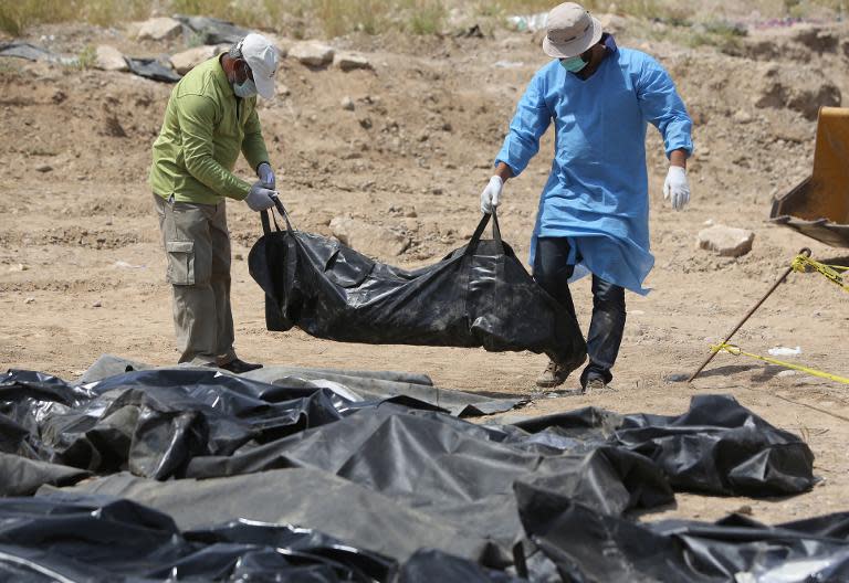 Iraqi security forces work at the site of a mass grave containing the remains of people believed to have been slain by Islamic State (IS) jihadists in Tikrit, on April 12, 2015