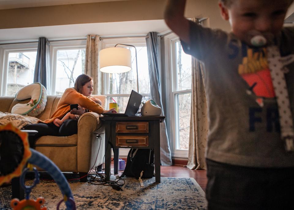 Dr. Elizabeth Bergamini, pediatrician in suburban St. Louis, searches online for open COVID-19 vaccine appointments while holding her 4-month-old son, Louis, and supervising her 2-year-old son, James Jerome, at her home in Wildwood, Mo., on March 11, 2021. Bergamini drove about 30 people to often out-of-the way vaccination events after the state opened eligibility to those 65 and older Jan. 18 and then expanded further. (Sara Diggins/St. Louis Post-Dispatch via AP)