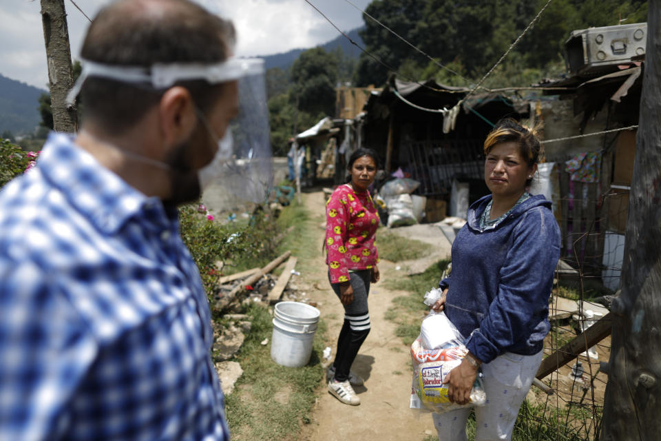 Patricia Cruz Castillo, 28, accepts a bag of donated food and household items brought by Luis Gutierrez of De La Mano Hacemos Mas (Spanish for Hand In Hand We Accomplish More), in Piedra Grande, Huixquilucan, Mexico State, Wednesday, June 17, 2020. Though the hillside community has so far felt isolated from the virus that causes COVID-19, the economic effects are widespread, with many inhabitants having lost their jobs in construction, farming, domestic work, and businesses that have been forced to close. (AP Photo/Rebecca Blackwell)