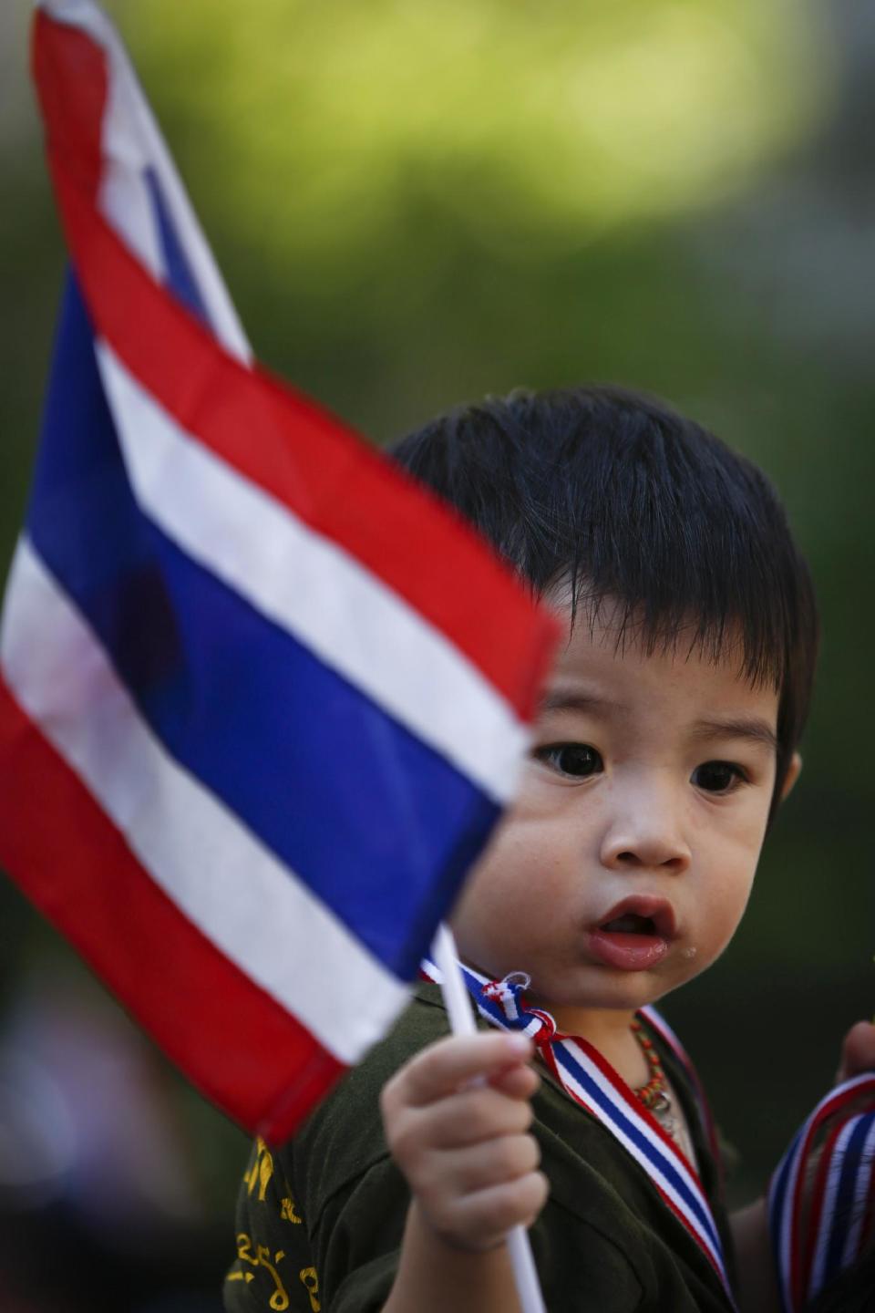 A boy waves a Thai national flag during an anti-government march towards the prime minister's office compound in Bangkok, Thailand, Monday, May 12, 2014. The battle for who holds Thailand's seat of power took on a new twist Monday as leader of anti-government protests Suthep Thaugsuban planned to set up his office at the vacated Government House while the country's new caretaker leader worked from a makeshift, suburban outpost. (AP Photo/Vincent Thian)