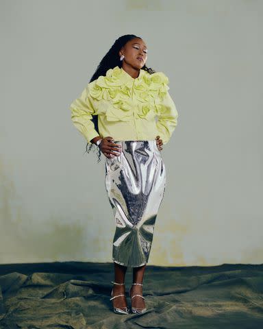 <p>Joshua Kissi</p> AKNVAS top and skirt, Leigh Miller earrings, Tag Heuer watch, and Larroude shoes.