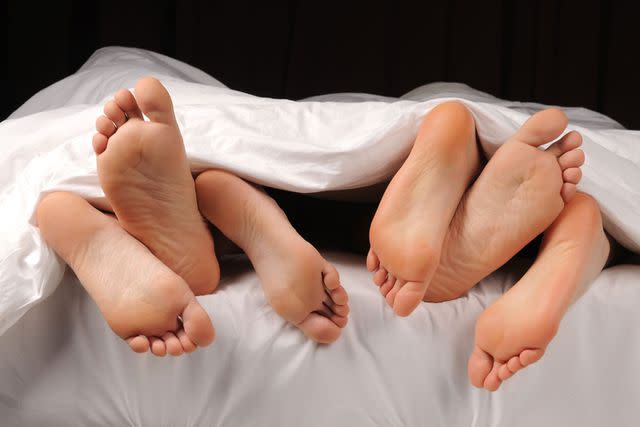 <p>Getty</p> Three sets of feet in a bed (stock image)