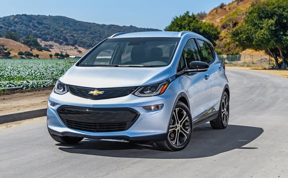 A 2018 Chevrolet Bolt EV, a compact electric vehicle, on a sunny coastal road.