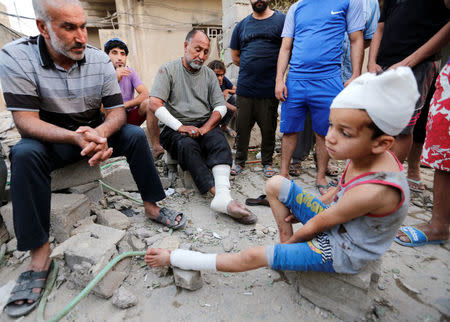 A man and his son, who were wounded, sit near the scene of an explosion in Baghdad's Sadr City district, Iraq June 7, 2018. REUTERS/Wissm al-Okili