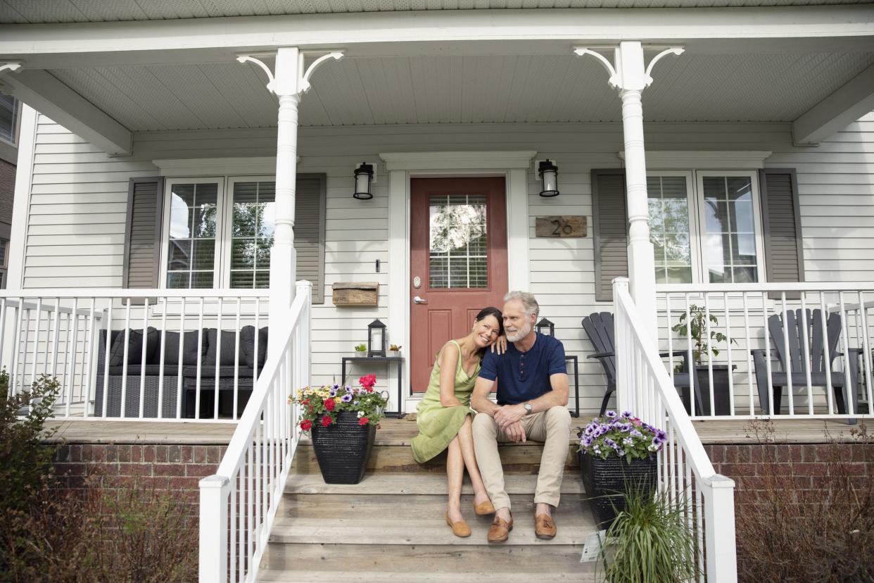 middle-aged couple sitting on steps in front of house