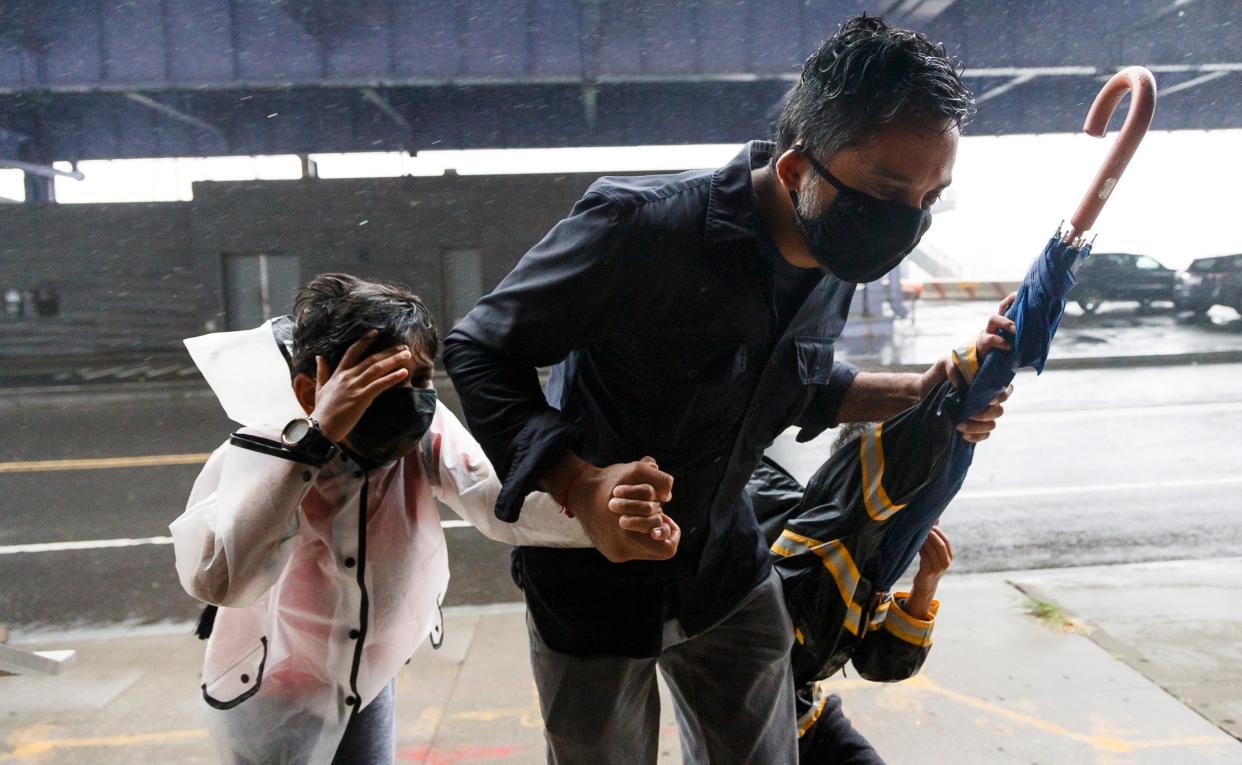 A man and his children try to find shelter from the wind in lower Manhattan as Tropical Storm Isaias passes through New York: EPA