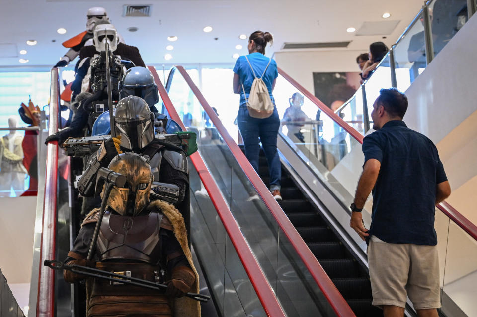 Costumed fans celebrating Star Wars Day ride escalators in Manila. 