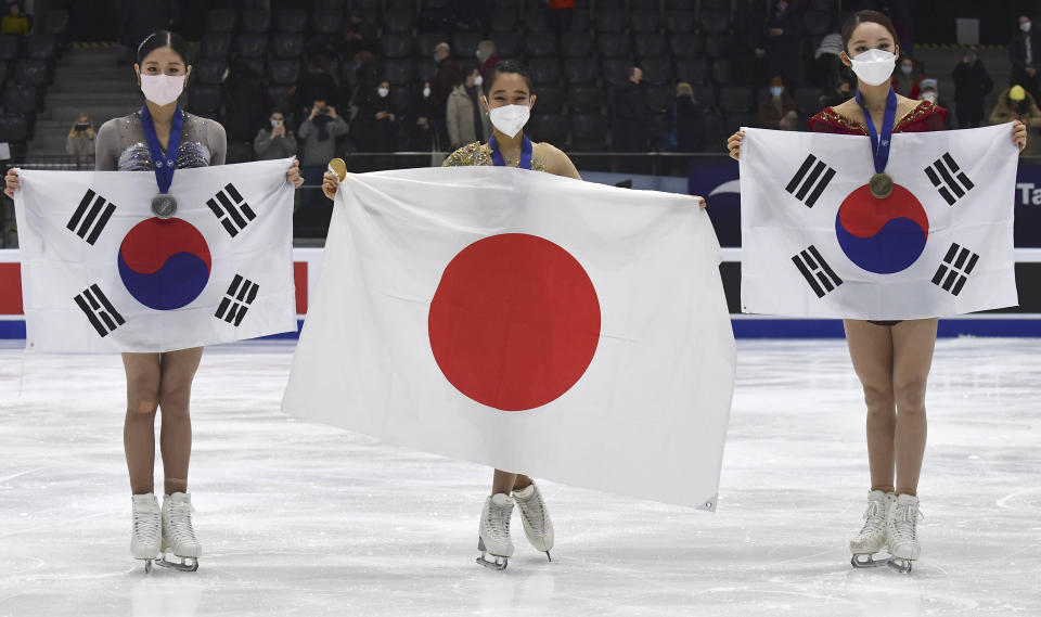 Mai Mihara of Japan, centre, first placed, Haein Lee of South Korea, second placed, left, Yelim Kim of South Korea, who finished third, pose with state flags after the women free skating program during the ISU Four Continents Figure Skating Championships in Tallinn, Estonia, Saturday, Jan. 22, 2022. (AP Photo/Sergei Stepanov)