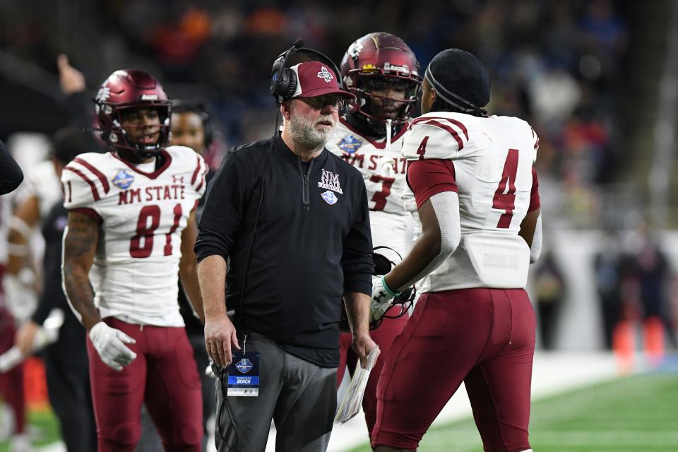 New Mexico State University head coach Jerry Kill, center, talks to players on the sidelines during the 2022 Quick Lane Bowl .