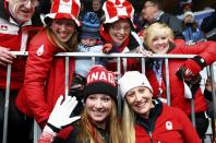 Canada's pilot Kaillie Humphries (R) and Heather Moyse (L) celebrate with family members after winning the women's bobsleigh event at the Sochi 2014 Winter Olympics February 19, 2014. REUTERS/Arnd Wiegmann (RUSSIA - Tags: OLYMPICS SPORT BOBSLEIGH)