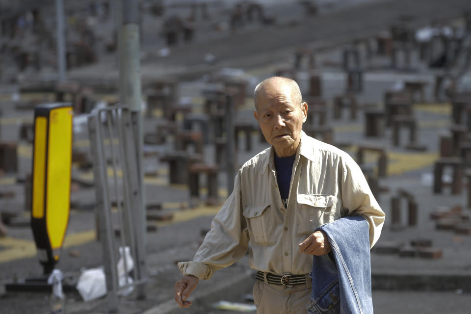 A man walks across a barricaded highway leading to the Cross Harbour Tunnel near the Hong Kong Polytechnic University in Hong Kong, Saturday, Nov. 16, 2019. Rebellious students and anti-government protesters abandoned their occupation of at least one major Hong Kong university after a near weeklong siege by police, but some other schools remained under control of demonstrators on Saturday. (AP Photo/Achmad Ibrahim)