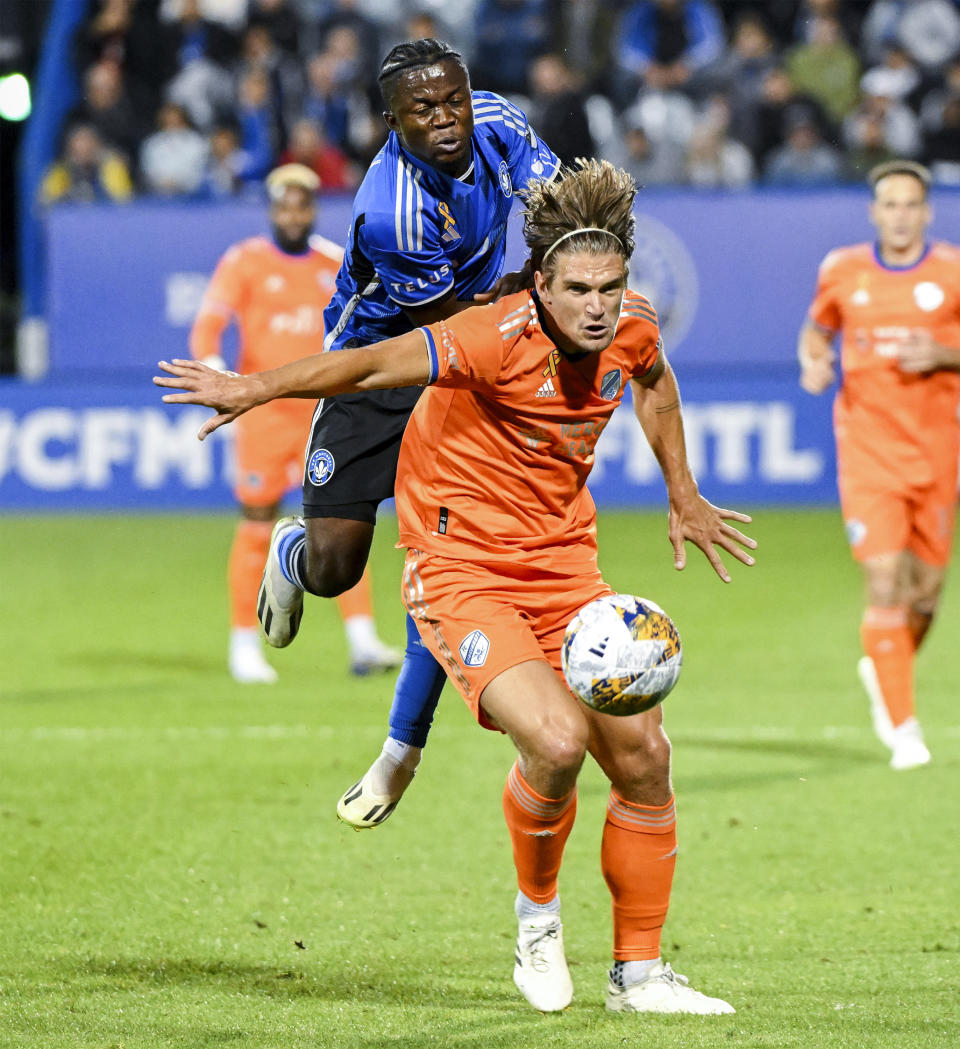 CF Montreal's Kwadwo Opoku, rear, works against FC Cincinnati's Nick Hagglund during the first half of an MLS soccer match Wednesday, Sept. 20, 2023, in Montreal. (Graham Hughes/The Canadian Press via AP)