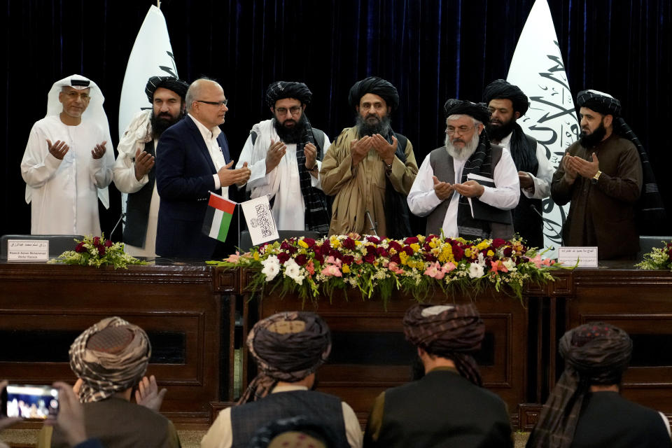 Mullah Abdul Ghani Baradar, Acting Deputy Prime Minister of the Afghan Taliban's caretaker government, center, and the chief financial officer of GAAC Solutions, Razack Aslam Mohammed Abdur Razack, second left, join others in a prayer during a document signing ceremony in Kabul, Afghanistan, Tuesday, May 24, 2022. The Taliban said Tuesday that they've signed a deal allowing Abu Dhabi-based GAAC Solutions to manage the airports in Herat, Kabul and Kandahar. (AP Photo/Ebrahim Noroozi)