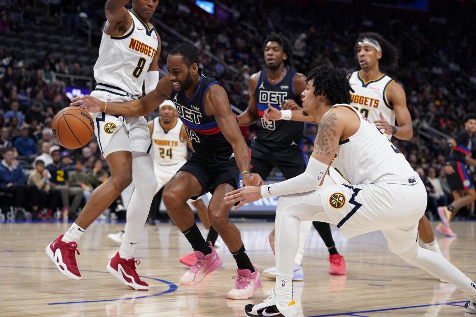 Detroit Pistons guard Alec Burks (14) drives between Denver Nuggets forward Peyton Watson (8) and guard Julian Strawther (3) during the first half of an NBA basketball game, Monday, Nov. 20, 2023, in Detroit. (AP Photo/Carlos Osorio)