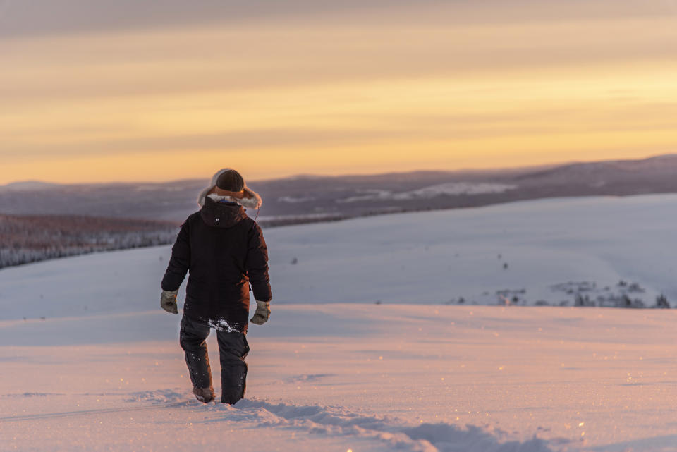 In this Wednesday, Nov. 27, 2019 photo, reindeer herder Niila Inga from the Laevas Sami community walks across the snow as the sun sets on Longastunturi mountain near Kiruna, Sweden. Global warming is threatening reindeer herding in Sweden’s arctic region as unusual weather patterns jeopardize the migrating animals’ grazing grounds as rainfall during the winter has led to thick layers of snowy ice that blocks access to food. (AP Photo/Malin Moberg)